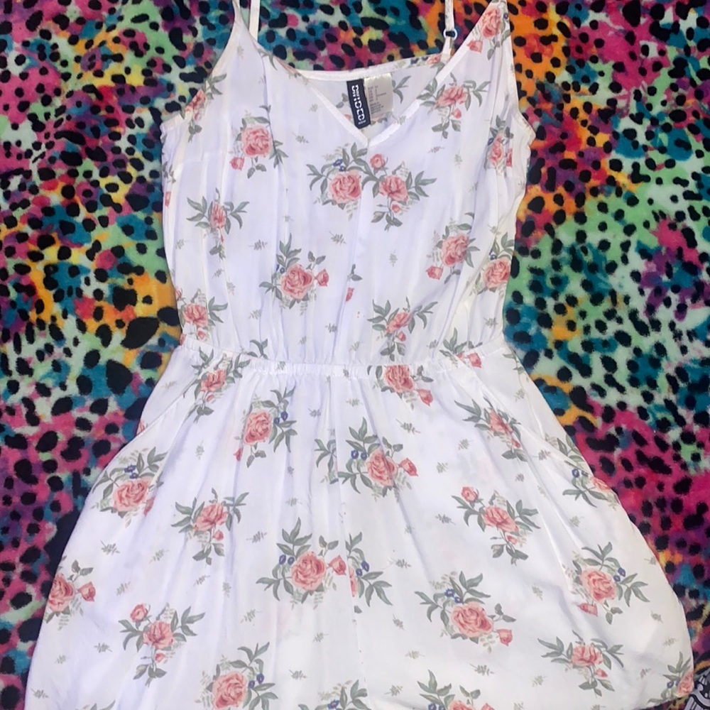 white floral romper w/ adjustable straps and front pockets.